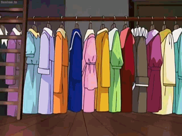 a bunch of colorful clothes are hanging on a rack in a closet