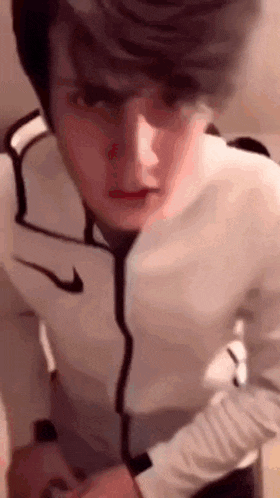 a man wearing a white nike jacket is standing in a room .