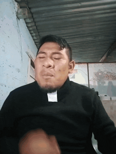 a man with his eyes closed wears a black shirt with a white tag on it that says ' trabajo educacion '