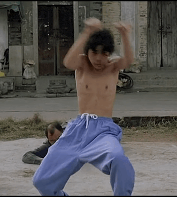 a shirtless man in blue pants is doing a karate move .