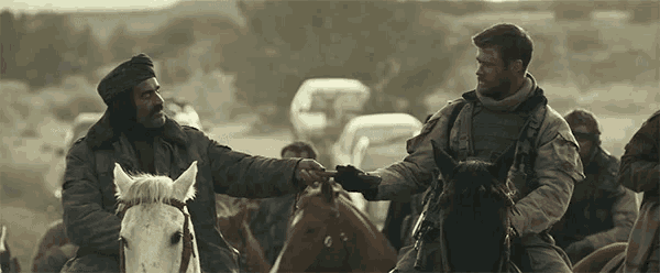 two men are riding horses and one of them is holding the hand of another man