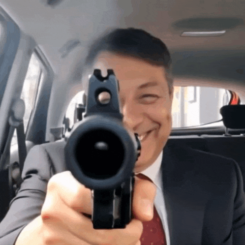 a man in a suit and tie is pointing a gun