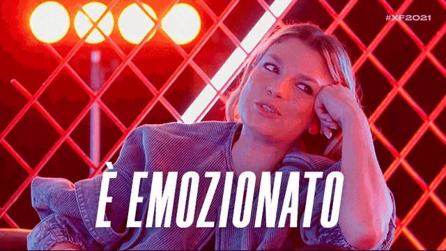 a woman sitting in front of a fence with the words e emozionato written on the bottom