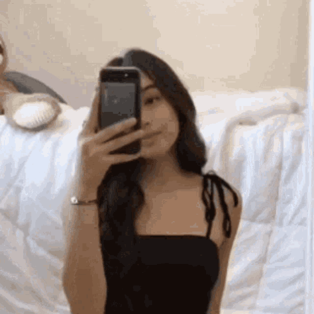 a woman is taking a selfie in a mirror with her cell phone .