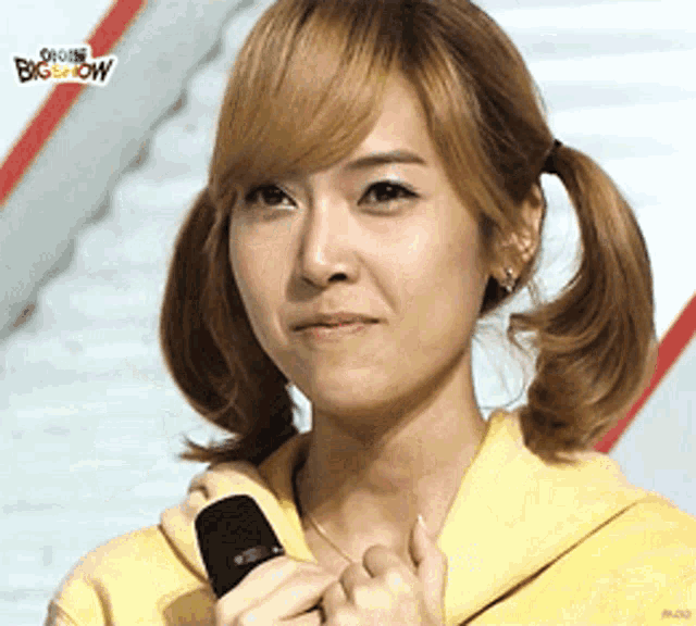a woman holds a microphone in front of a big show sign
