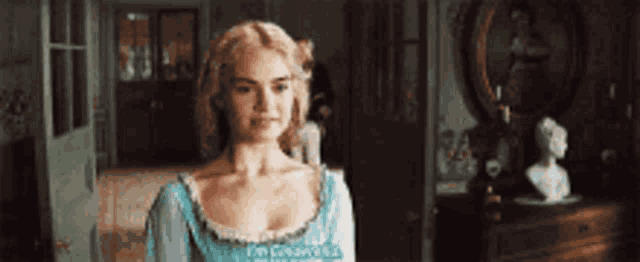 a woman in a blue dress is standing in a room with a bust in the background .