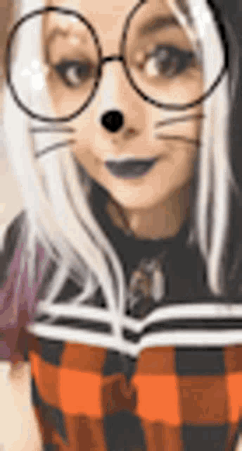 a woman wearing glasses and a plaid shirt is taking a selfie with a cat face filter .