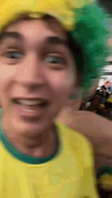 a man wearing a yellow shirt and green hat is smiling