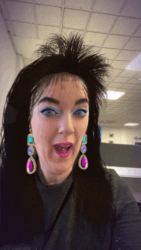 a woman is wearing a wig and earrings and making a funny face