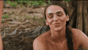 a woman without a shirt is making a funny face with her eyes closed