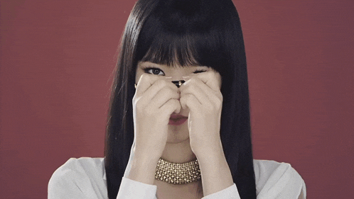 a woman covering her eyes with her hands and wearing a gold necklace