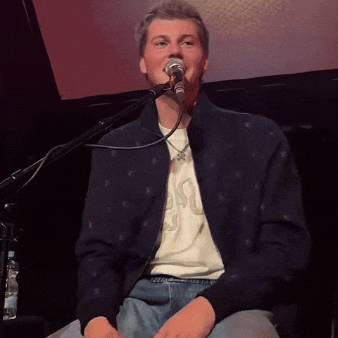 a man singing into a microphone wearing a shirt that says ' snake '