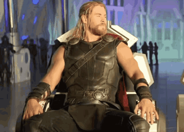 a man in a leather outfit is sitting on a throne with a shield on his belt