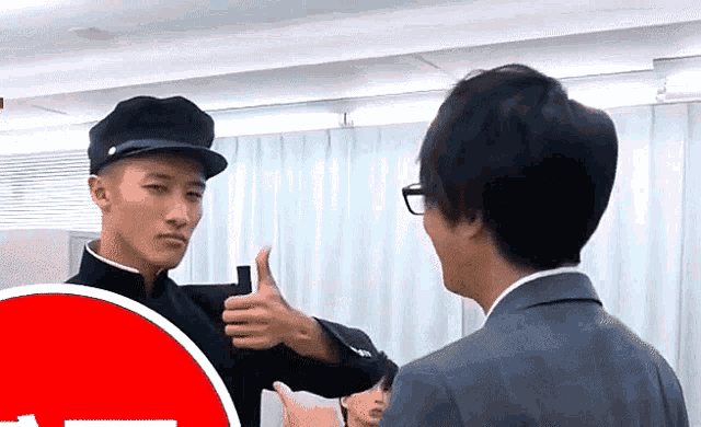 a man in a hat giving a thumbs up to another man