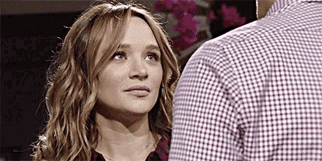a woman in a plaid shirt is looking at a man in a checkered shirt .