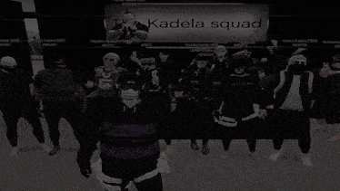 a group of people standing in front of a kadela squad banner