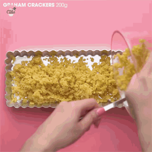 graham crackers are being poured into a pan on a pink surface