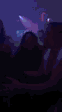 a blurry picture of a man and woman hugging in a crowded nightclub .