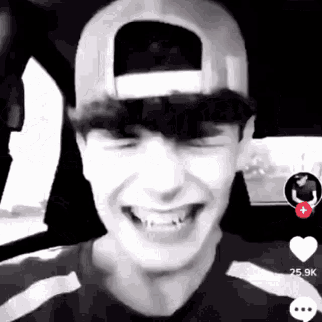 a man wearing a baseball cap is laughing in a car .