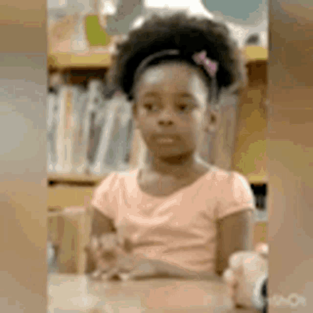 a young girl is sitting at a desk in a classroom .