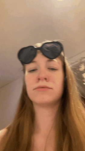 a woman wearing sunglasses makes a funny face