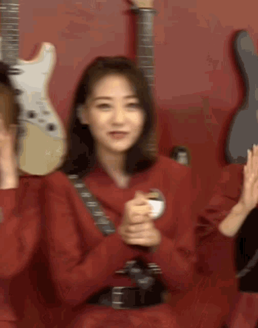 a woman in a red jacket is standing in front of a wall of guitars .