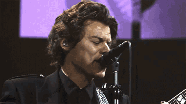 a man singing into a microphone while wearing a black suit