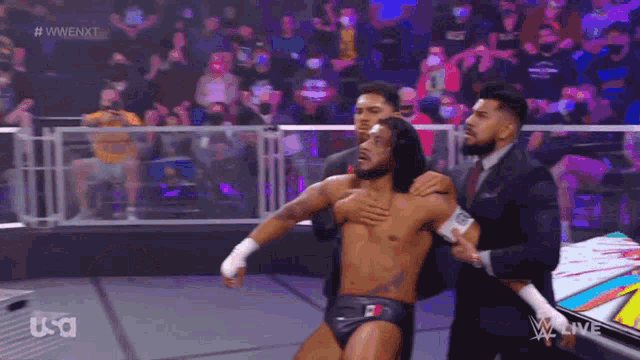 a man in a suit is holding another man in a wrestling match