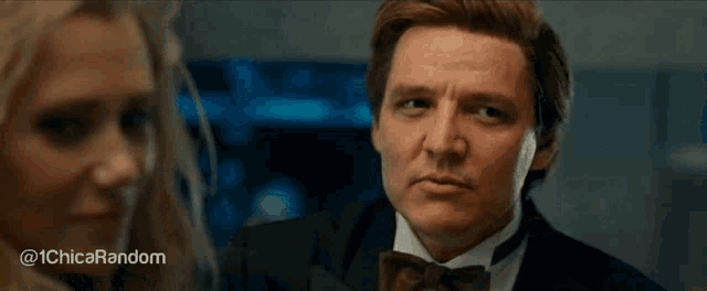 a man in a suit and bow tie is talking to a woman .