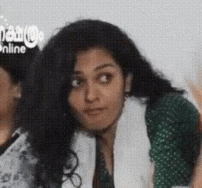 a woman with long hair is making a funny face while wearing a green shirt and a white scarf .