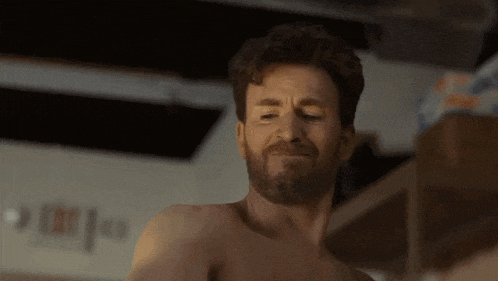 a shirtless man with a beard is standing in a room .