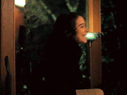 a woman is sitting in a dark room looking out the window