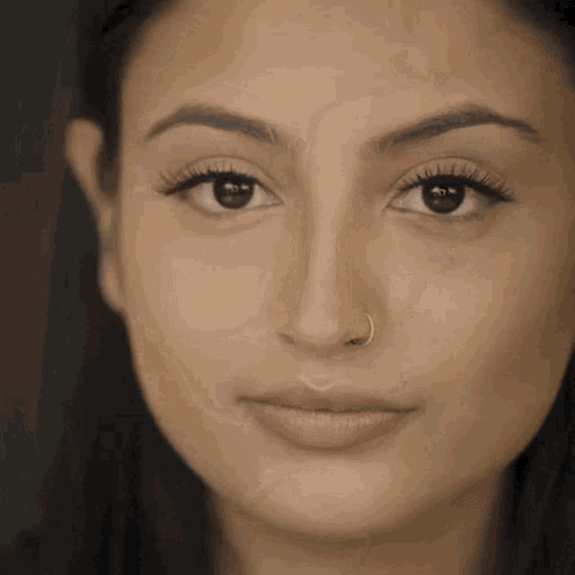 a woman with a nose ring is looking at the camera