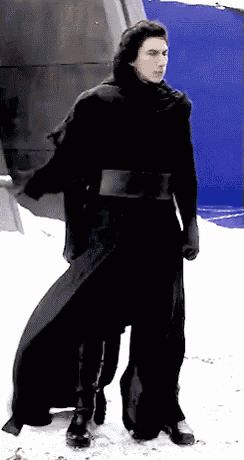 a man in a black coat is standing in the snow .