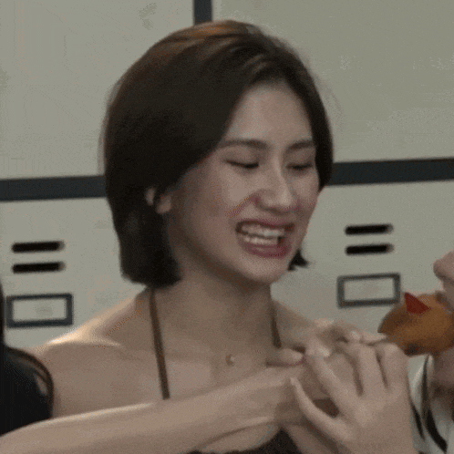 a close up of a woman making a funny face while holding a donut .
