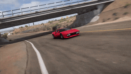 a red sports car driving under a bridge