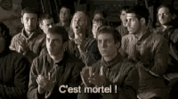 a group of people are sitting in a room and applauding with the words c'est mortel written on the screen .