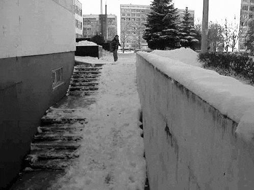 a black and white photo of a person jumping over a snowy wall .