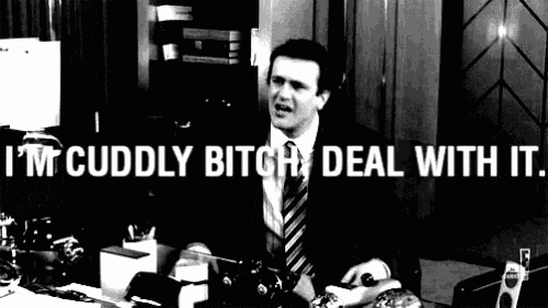 a man in a suit and tie is sitting at a desk with the words i 'm cuddly bitch deal with it above him