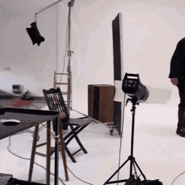 a man is standing in a photo studio with a light on a stand