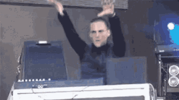 a man is sitting at a desk with his arms in the air .