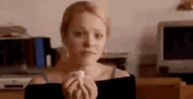 a woman is holding a tissue in her hand in front of a television .