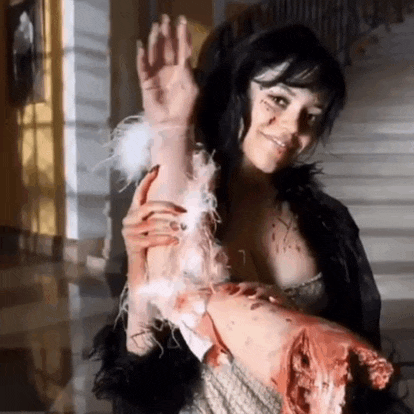 a woman is holding a bloody arm and smiling .