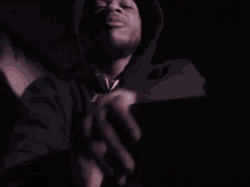 a man in a black hoodie is taking a selfie in a dark room .