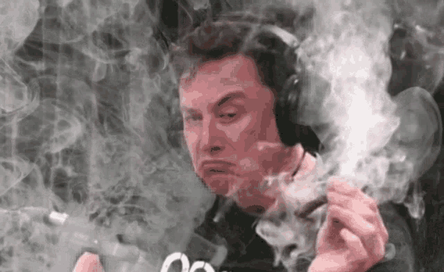 elon musk is smoking a cigarette while wearing headphones and making a funny face .
