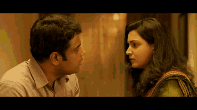 a man and woman are looking at each other in a dark room
