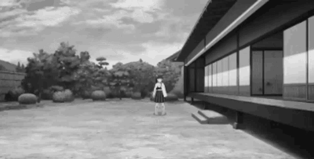 a black and white photo of a girl standing in front of a large building