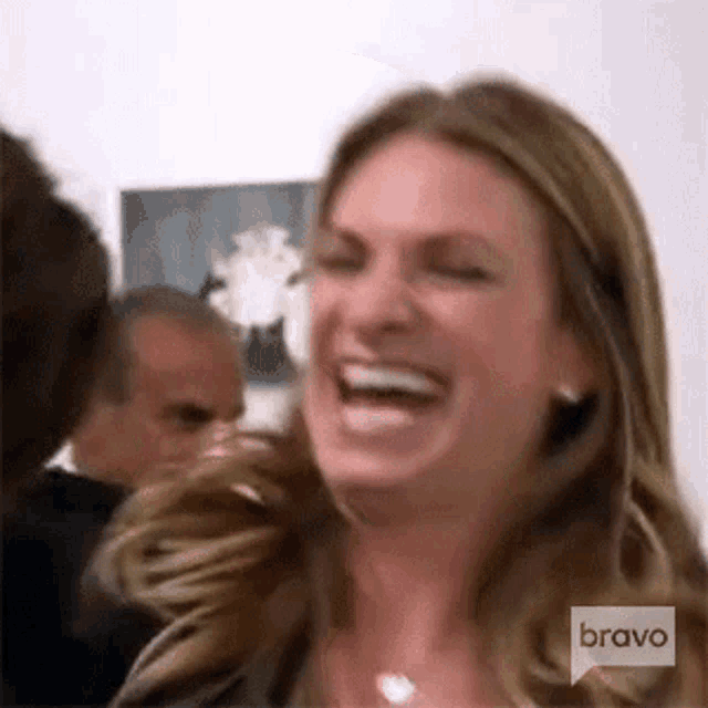 a woman is laughing with her mouth open while standing in front of a group of people .