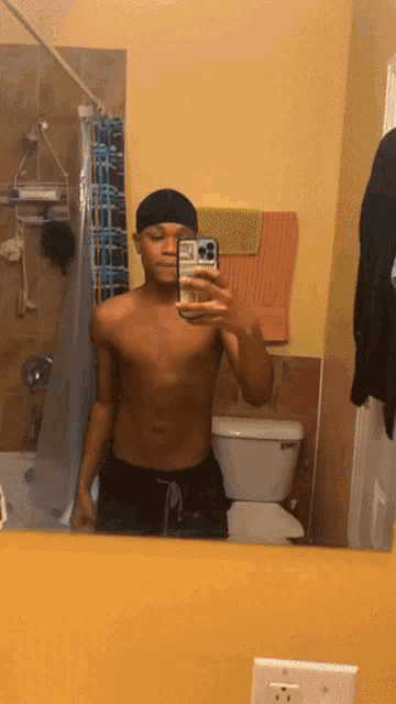 a shirtless man taking a selfie in a bathroom mirror