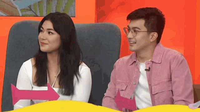 a man and a woman are sitting next to each other and smiling .